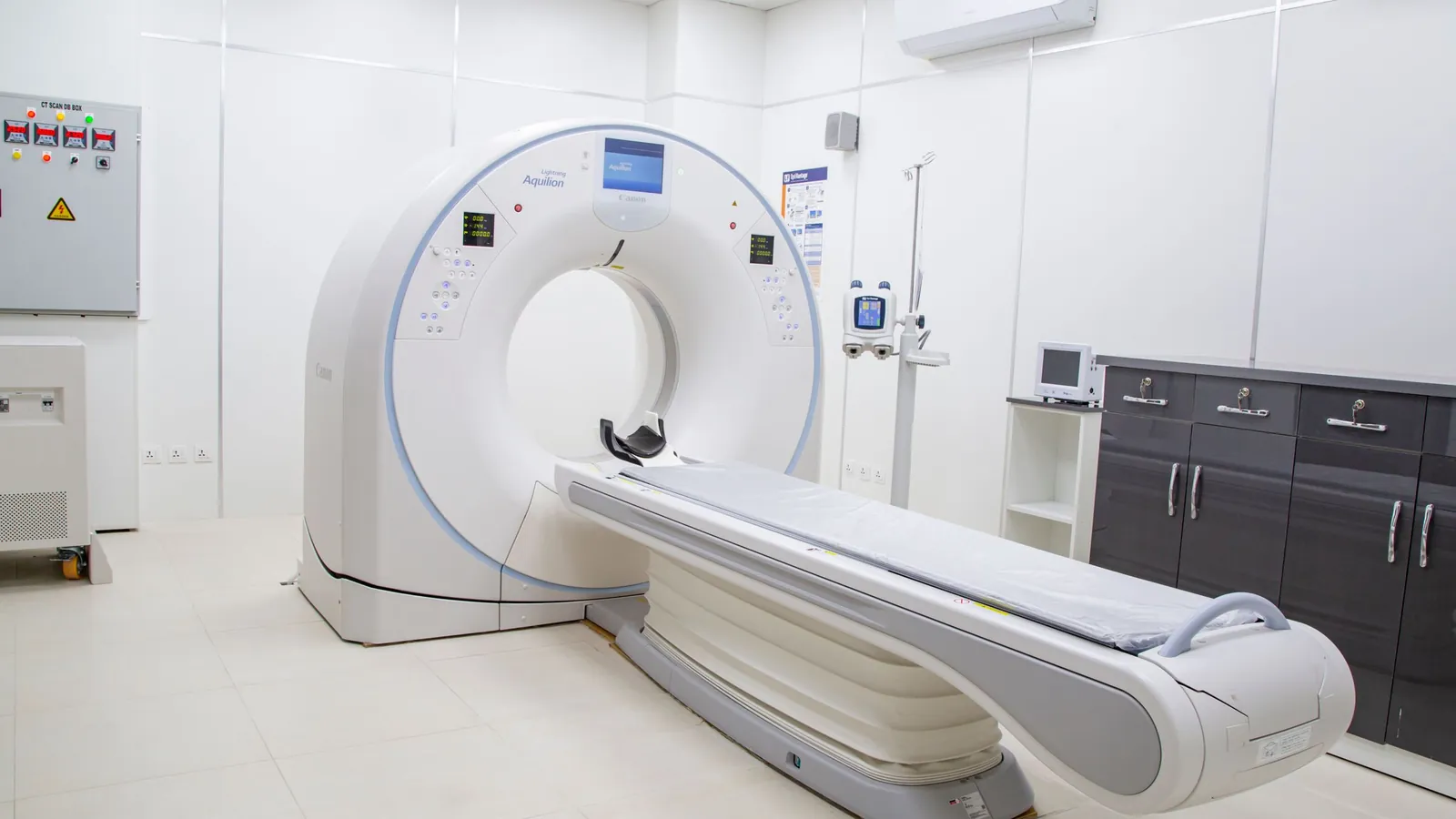 An empty CT scanner room with the patient table in front of the scanner