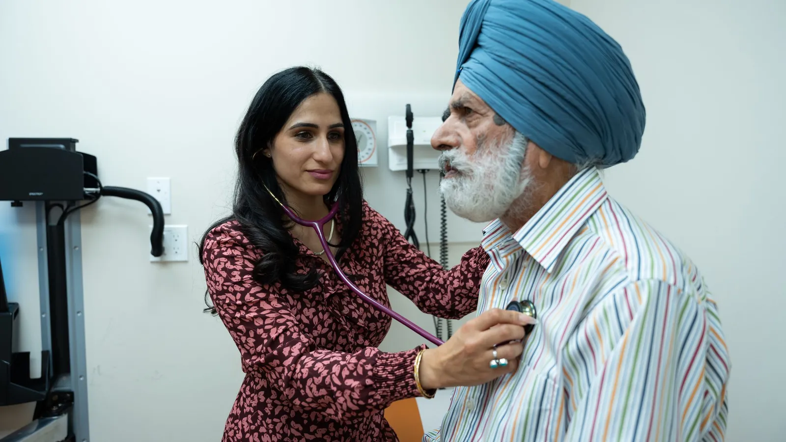 A doctor checks an elderly man's heartbeat with a stethoscope