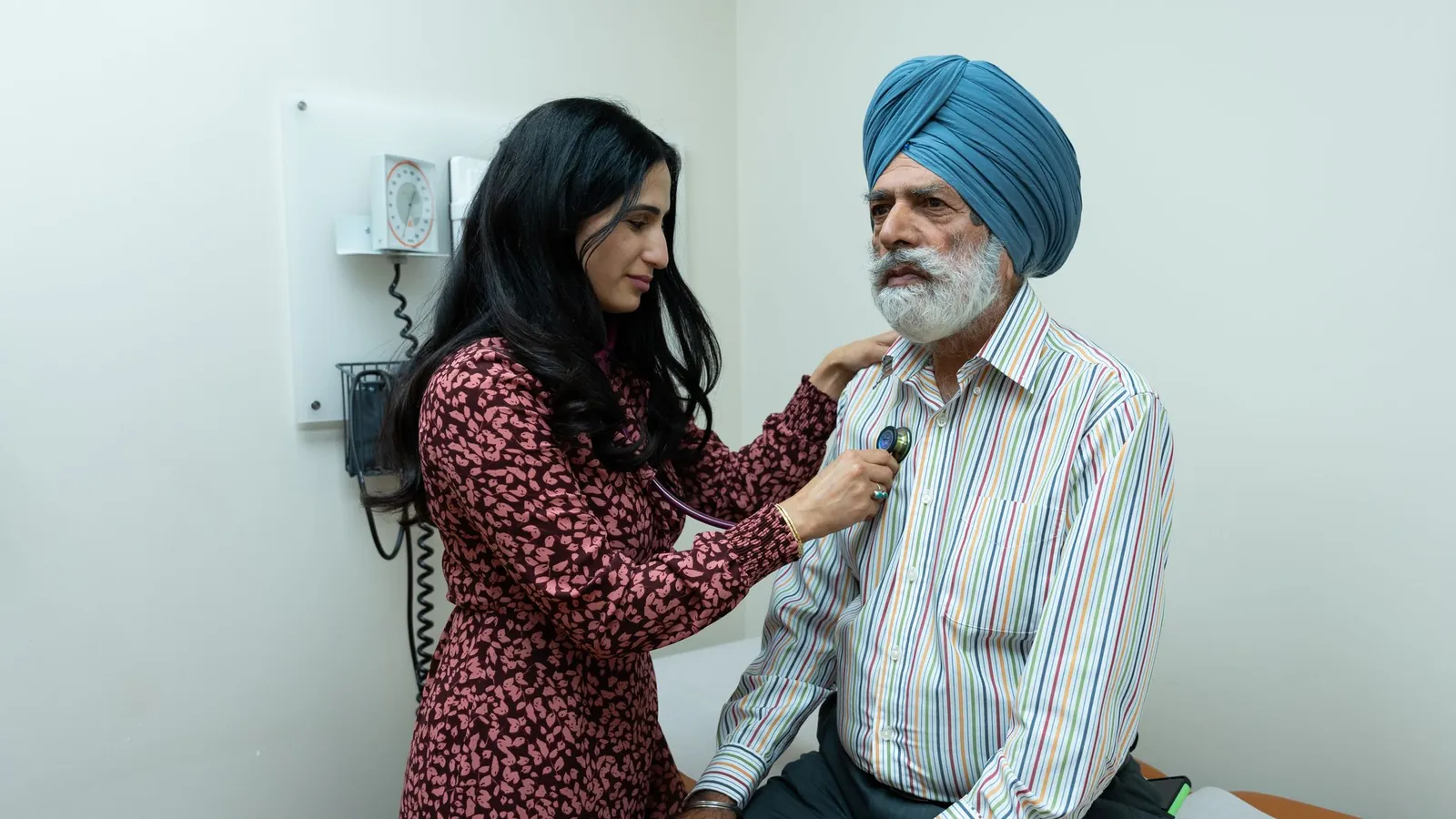 A health worker listens to an elderly man's chest with a stethoscope
